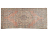 Distressed vintage Oushak runner featuring a pale blush field and muted pattern.