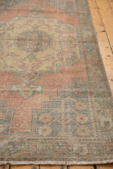 Distressed vintage Oushak runner with faded blush, aqua, and green worn pile.