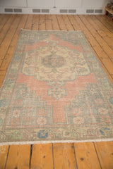 Distressed Oushak runner corner, pale blush spandrel, aqua border, and delicate plant motifs.
