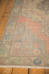 Decorative distressed border of a vintage Oushak runner with pale blush and aqua tones.