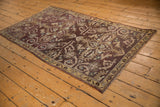 Distressed vintage Oushak rug corner, revealing aubergine, beige, and aqua tones with faint foundation showing.