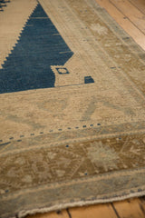 Distressed vintage Oushak detail: worn beige field, navy motif, pale bronze border.