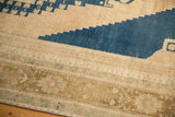 Even wear reveals stepped navy blue motif and geometric border on a distressed vintage Oushak.