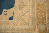 Distressed vintage Oushak carpet with navy field, geometric motifs, and a beige border.