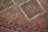 Distressed vintage Oushak rug corner: faded rust field, charcoal border, and visible knot heads.