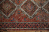 Distressed Oushak rug close-up, featuring worn red pile and geometric dark border.