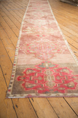 Distressed Oushak runner's secured end, with fuchsia scalloped medallion and abrashed texture.