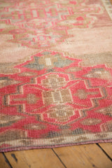 Distressed pile texture with fuchsia, beige, and soft blue geometric patterns on vintage Oushak runner.