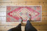 Distressed vintage Oushak runner's geometric stepped medallion with blush cherry red and ivory.