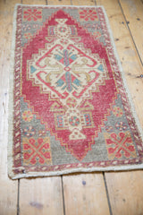 Distressed hand-knotted Turkish Oushak rug corner, showing worn cherry red, ivory, and gray geometric pattern.