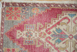 Distressed Oushak rug corner with blush cherry red, ivory, and gray stepped geometric motifs.