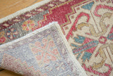 Distressed Oushak rug corner revealing its worn cherry red pile and hand-knotted foundation.