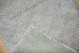 Distressed low pile surface of a silver Oushak rug, revealing its hand-knotted foundation.