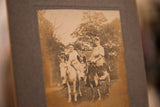 Angled view of an antique sepia photograph revealing the texture of its paperboard mount.