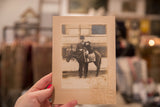 Antique black and white photograph held by hand, revealing textured mat border and age staining.