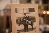 Sepia-toned antique photograph of child on horse, showing textured mat border and patina.