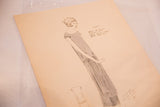 Angled view of antique 1920s hand-colored fashion art, highlighting handwritten text.