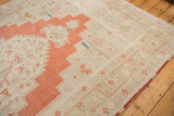 Textured distressed Oushak rug showing burnt orange medallion and soft ivory-beige field.
