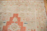 Distressed Oushak rug, detail of burnt orange medallion and light beige field motifs.