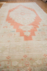 Faded burnt orange and sand motifs on the distressed border of a vintage Oushak rug.