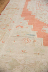 Distressed vintage Oushak rug showing antique ivory field and burnt orange serrated border.