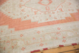 Distressed Oushak rug with faded burnt orange and antique ivory geometric patterns.