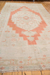 Distressed vintage Oushak carpet corner with fringe, burnt orange, and antique ivory field.