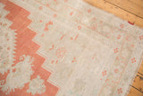 Muted burnt orange and antique ivory stylized patterns on a distressed Oushak rug's border.