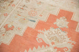 Burnt orange geometric border and faded floral motifs on a distressed vintage Oushak.