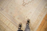 Distressed Oushak rug detail: abrashed neutral field, germinating flowers, pale blue spandrel.