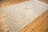 Distressed vintage Oushak rug corner, showing ivory field, beige border patterns, and abrashed texture.