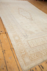 Distressed Oushak corner with beige geometric border and subtle germinating flower spandrel.