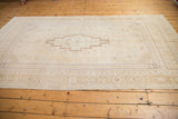 Distressed Oushak rug's lower border, showcasing muted beige patterns and soft abrashed field.
