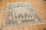 Distressed Oushak rug corner with muted green stylized floral motifs and soft ivory pile.