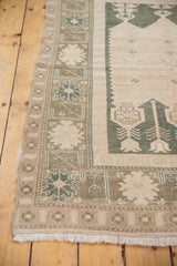 Ivory fringes and stylized geometric border of a distressed Oushak rug.
