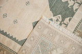 Distressed Oushak rug showing hand-knotted reverse and low ivory pile with charcoal design.