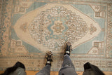 Vintage distressed Oushak rug with pale ocean blue geometric medallion and low pile.