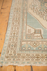 Intricate pale ocean blue and sand geometric border on a vintage distressed Oushak rug.