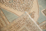 Folded vintage Oushak rug, showing low pile, pale blue geometric border, and woven reverse.