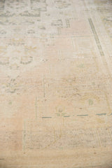 Distressed low pile on a vintage Oushak carpet with ivory, beige, and seafoam geometric patterns.