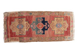 Distressed vintage Oushak runner showcases primitive floral geometric medallions in raspberry red, beige, and navy, 1'7