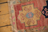 Distressed Oushak rug's fringed edge and border with blush, gold, and sky blue primitive motifs.