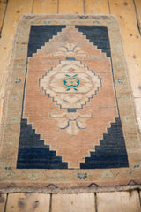 Stepped navy and beige diamond medallion with teal motifs on a distressed Turkish Oushak rug.