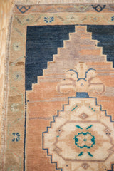 Distressed Oushak rug detail showing stepped end finial in navy blue, beige, and apricot.