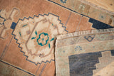 Distressed Oushak rug pile with beige stepped border, teal accents, fringe, and woven reverse.