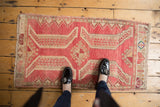 Distressed Oushak rug, central pinwheel medallion and sprawling leaf pattern in muted red and beige.