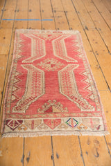 Distressed Oushak rug with decorative fringe and colorful geometric border.