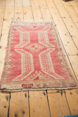 Distressed vintage Oushak rug, showing worn raspberry red and beige sprawling leaf patterns.