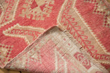Distressed vintage Oushak rug pile in raspberry and beige, revealing hand-knotted reverse and fringe.