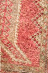 Distressed Oushak rug pile showcasing raspberry red and beige tones with textured knots.